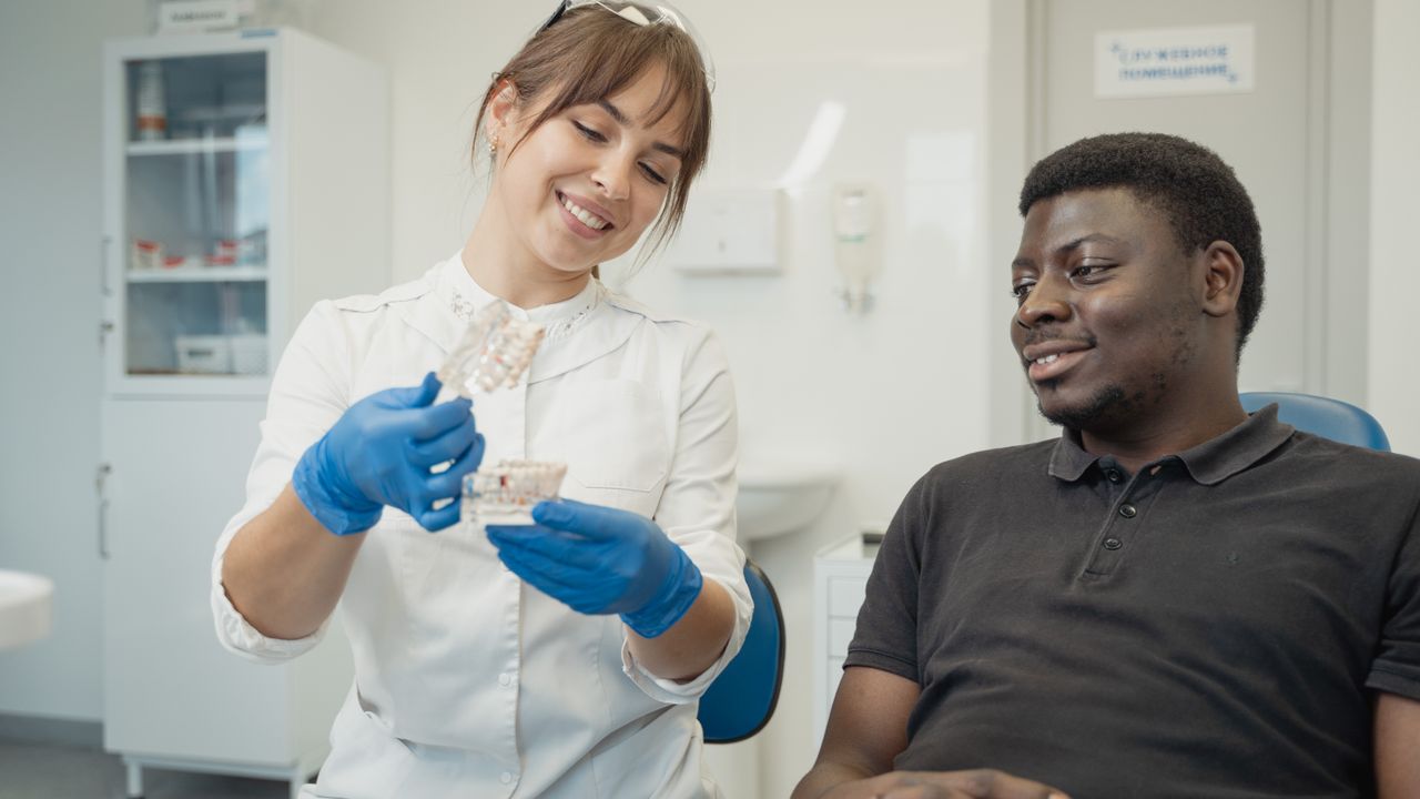 Dentist explaining a dental model to a patient during a consultation, the kind of appointment dental work abroad is planned around