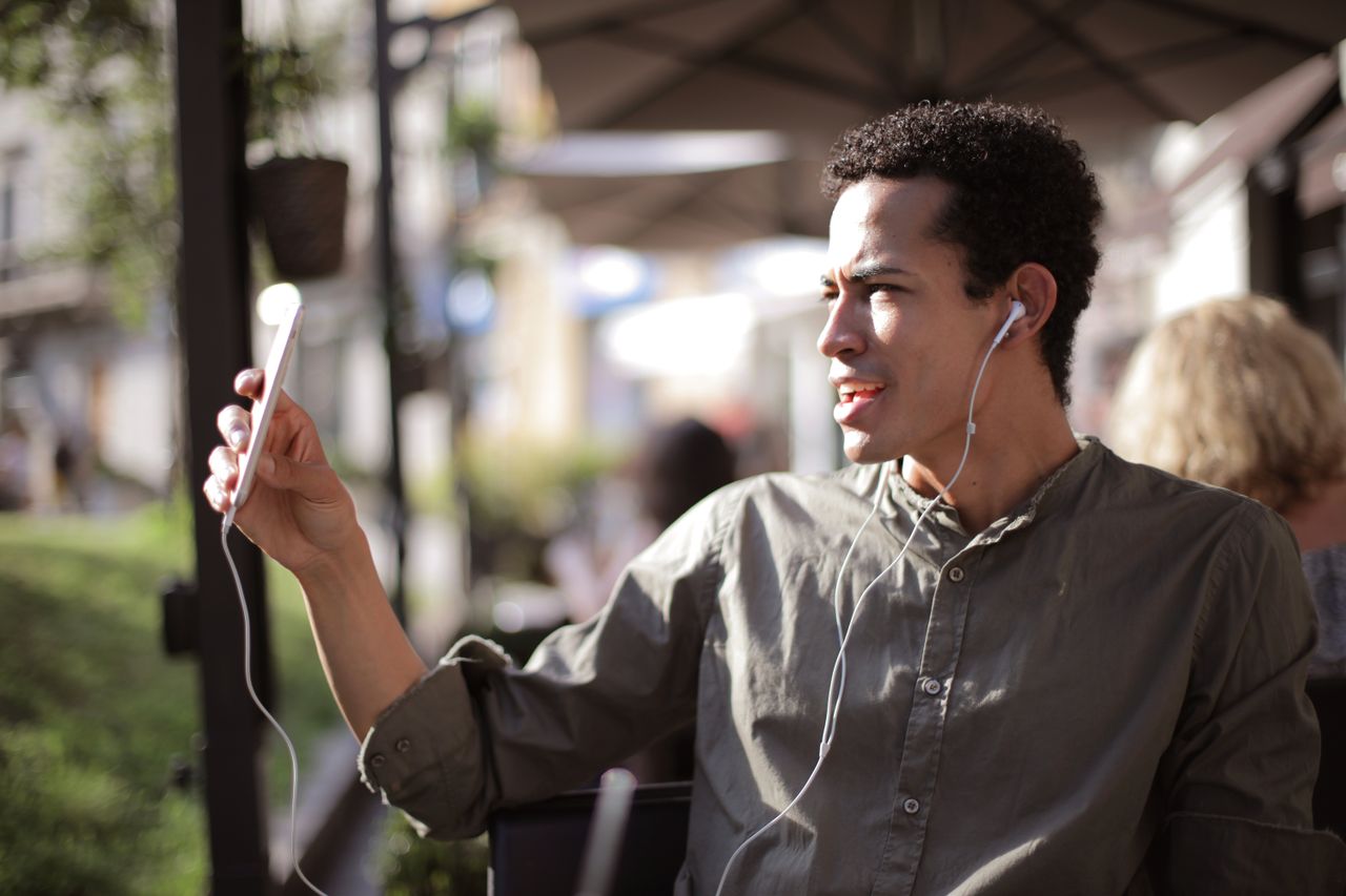 Man on outdoor terrace using smartphone for video call while traveling abroad — mobile data needed for WhatsApp and FaceTime